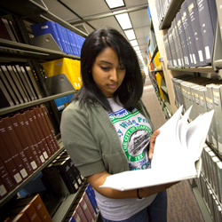 Student reading a book in the library stacks.